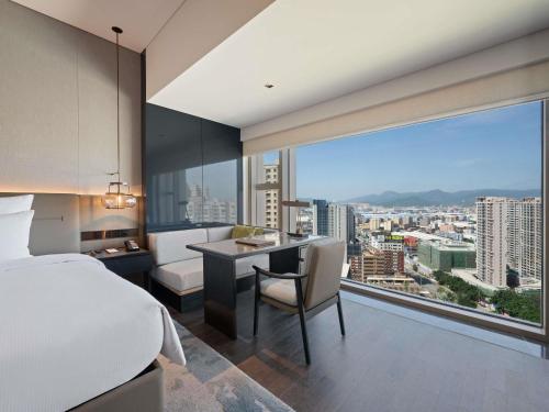 a bedroom with a bed and a desk and a large window at Pullman Quanzhou Shuitou in Quanzhou