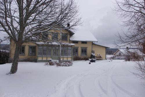 a house with a snow covered driveway in front of it at Perssons Magasin in Västra Löa