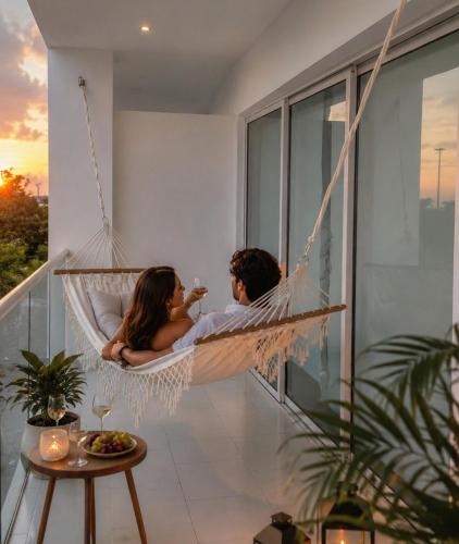 a man and woman sitting in a hammock on a balcony at Morros 3 Frente al Mar - Piscinas y Jacuzzi in Cartagena de Indias