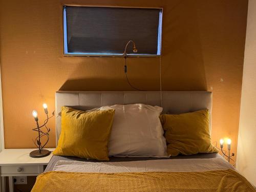 a bed with yellow and white pillows and a window at Apartment Osso 2, Arnhem in Arnhem