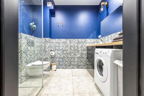a bathroom with blue walls and a washing machine at Plac Solny 4 Discreet&Comfort Głogów in Głogów