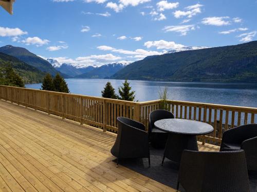 a table and chairs on a deck with a view of a lake at Faleide Panorama Private Fjord View Cabin with Large Terrace in Stryn