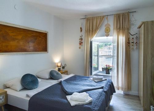 a bedroom with a bed with blue pillows and a window at Apartments Coli app Afrodita & Antonia & Veronika in Bakar
