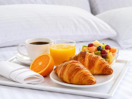 a breakfast tray with croissants fruit and orange juice at Hotel Mediterraneo Quito in Quito