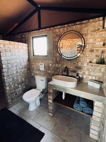 a bathroom with a toilet and a sink and a mirror at Orpheus Inn & Glamping in Kaneb Pos