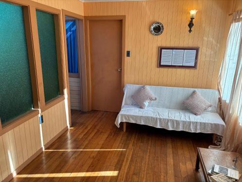 a living room with a white couch and wood floors at Casa Mañío Hostal Castro in Castro