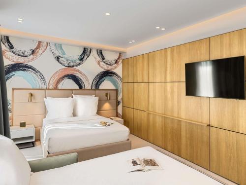 a hotel room with a bed and a flat screen tv at Mercure Tirana in Tirana