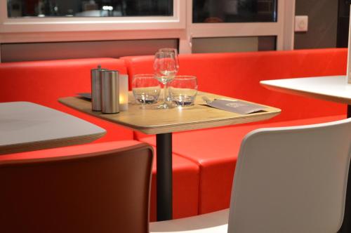 a table with wine glasses on a red couch at ibis Honfleur in Honfleur