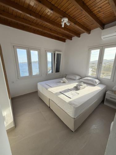 a white bedroom with a large bed with windows at The Aegean Horizon Villa in Grótta