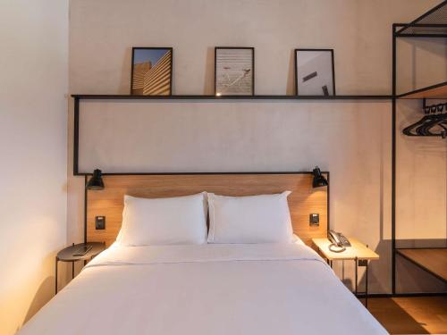 a bedroom with a white bed with shelves above it at ibis Tubarão in Tubarão