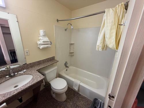 a bathroom with a toilet and a sink and a tub at Encore Motel in Farmington