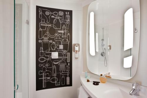 a bathroom with a black and white pattern on the wall at ibis Honfleur in Honfleur