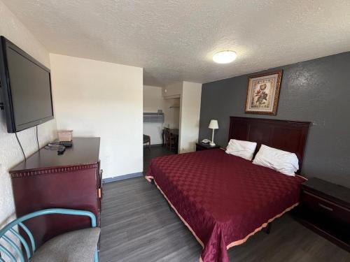 a hotel room with a bed and a flat screen tv at Encore Motel in Farmington