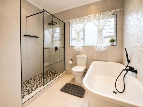 a bathroom with a shower and a toilet and a tub at Umhlanga La Lucia Oasis, Family Friendly Accommodation in Durban