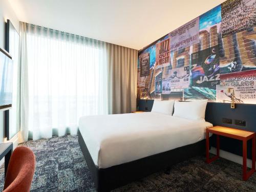 a hotel room with a large bed and a large mural at ibis Styles Melbourne Airport in Melbourne