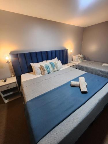 two beds in a bedroom with a blue headboard at Essencial Hotel Spa in Mendoza