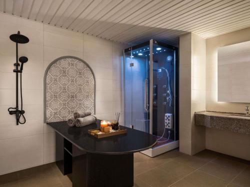 a bathroom with a shower with a table and candles at Mercure Muscat in Muscat