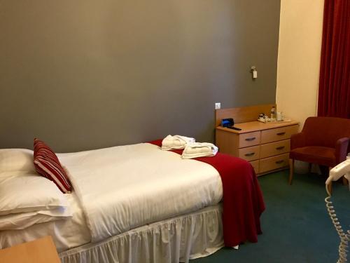a bedroom with a bed and a dresser and a chair at Glenlossie Guest House in Dumfries