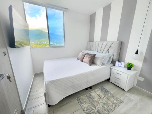 a white bedroom with a bed and a window at Apartamento Paradise in Ibagué