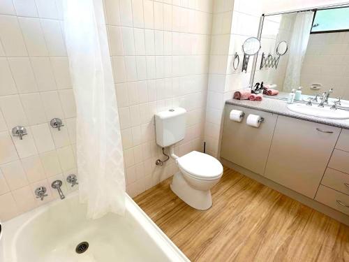 a bathroom with a toilet and a sink and a tub at Heavenly Views in Airlie Beach