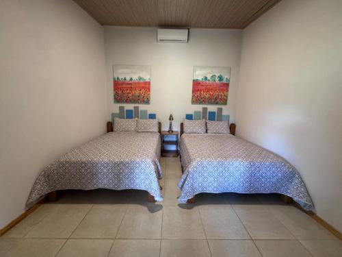 a room with two beds and two paintings on the wall at Tropical Haus CR - La Central in Puerto Jiménez