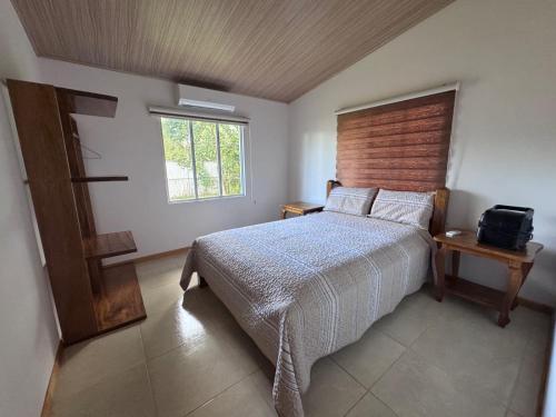 a bedroom with a bed with a wooden headboard and a window at Tropical Haus CR - La Central in Puerto Jiménez