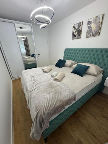 a bedroom with a large bed with a blue headboard at Apartment Lumos in Ljubuški