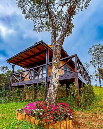 a house with a tree and flowers in front of it at Cabana Zermatt in Timbe do Sul