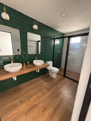 a green tiled bathroom with two sinks and a toilet at Residencia familiar céntrica xalapa in Xalapa