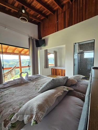 a bedroom with a large bed with a large window at Oasis na montanha in Bueno Brandão