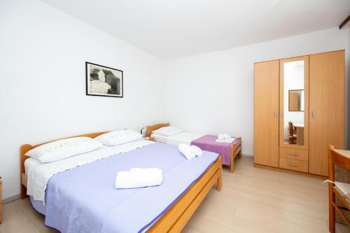 a bedroom with two beds with white sheets at Apartments by the sea Stara Novalja, Pag - 6301 in Stara Novalja