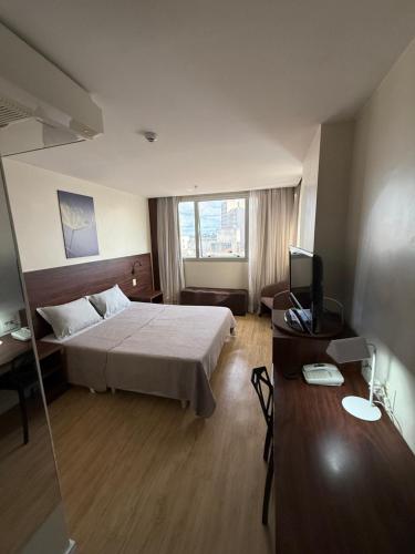 a hotel room with a bed and a television at Flat em Taguatinga in Taguatinga