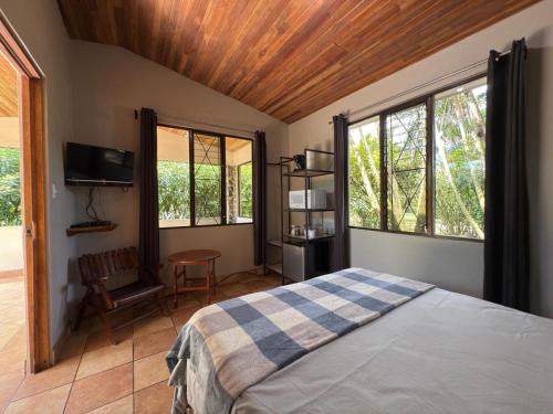 a bedroom with a bed and windows and a chair at Lago Vida Cabins in Tilarán