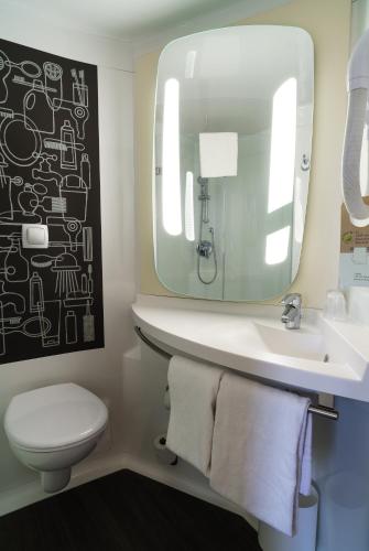 a bathroom with a sink and a toilet and a mirror at ibis Honfleur in Honfleur