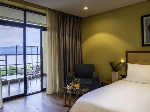 a hotel room with a bed and a balcony at Mantis Kivu Marina Bay Hotel in Muhari