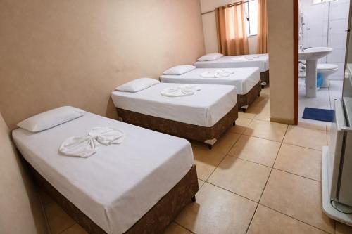 a group of four beds in a room at Hotel Benfica in Aparecida