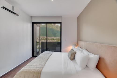 a bedroom with a white bed with a large window at Nido x Gran Ciudad Nuevo Sur in Monterrey