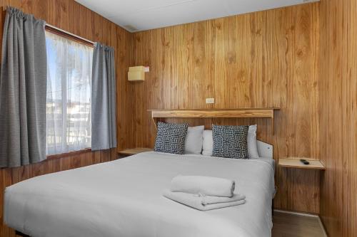 a bedroom with a white bed and wooden walls at Apollo Bay Holiday Park in Apollo Bay