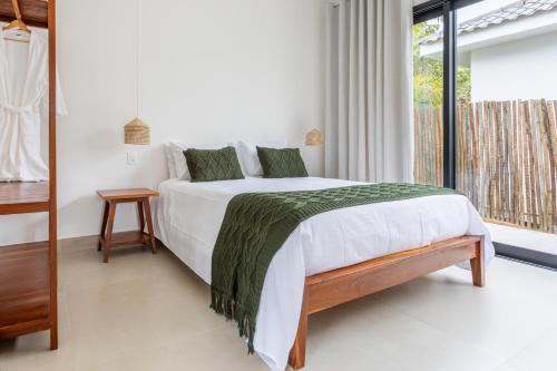 a bedroom with a white bed with a green blanket at Botanique Veadeiros in Alto Paraíso de Goiás