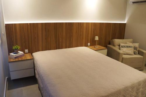 a bedroom with a large bed and a chair at Studio moderno no coração da Cidade Baixa in Porto Alegre