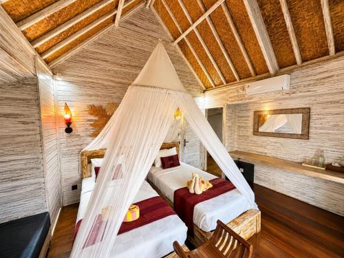 a bedroom with two beds and a hammock in a room at Nanuk's Bungalows in Nusa Lembongan