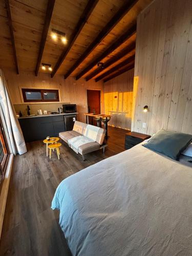 a bedroom with a large bed and a kitchen at Piedra Amarilla Tiny House in Curanipe