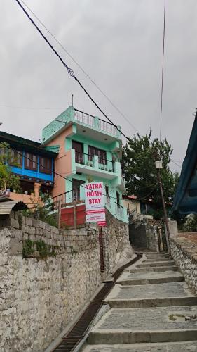 a building with signs in front of a stone wall at Yatra Homestay in Joshīmath