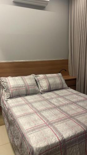 a bedroom with a bed with a plaid comforter at Apartamento ao lado do Mercado Central Edifício Fidelis in Goiânia