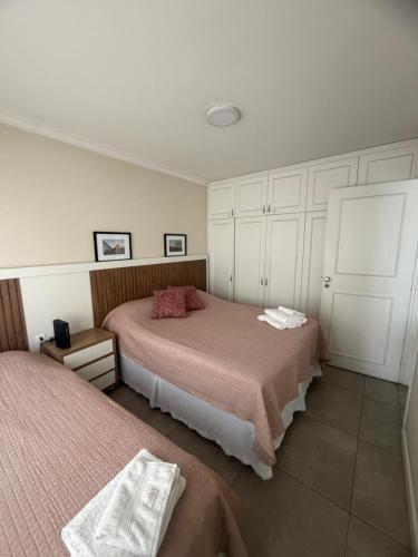 a bedroom with two beds and white cabinets at Apartamento central, novo e com garagem em Curitiba in Curitiba