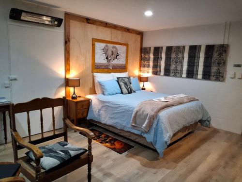 a bedroom with a bed and a chair at TePopo Gardens Rural Retreat in Stratford