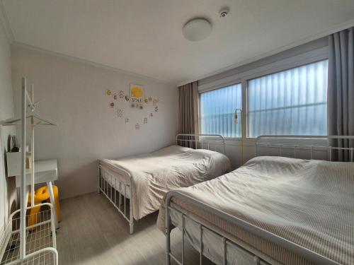 a bedroom with two beds and a window at Suwon Cozy Stay in Suwŏn-yŏk