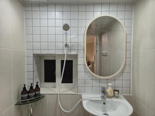 a white bathroom with a sink and a mirror at Suwon Cozy Stay in Suwŏn-yŏk