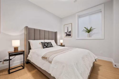 a white bedroom with a large bed and a window at The North Shore Luxe Suite in North Vancouver
