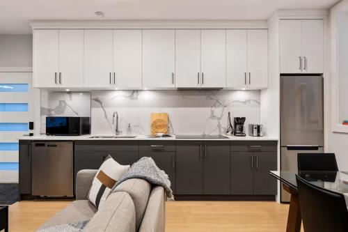 a kitchen with white cabinets and a couch in a room at The North Shore Luxe Suite in North Vancouver